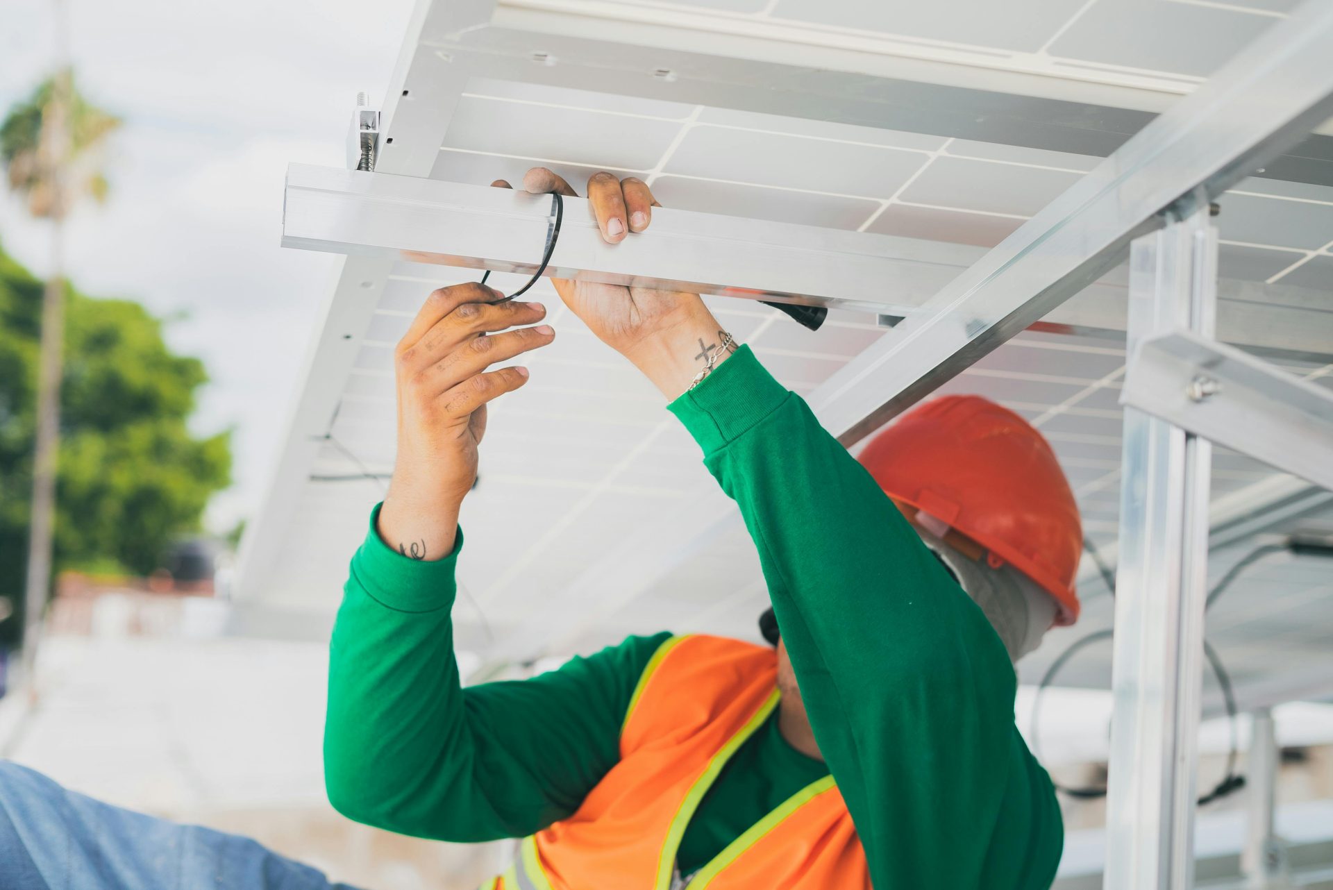 Un técnico solar con equipo de protección personal instala un panel solar, mostrando así el trabajo que se realiza en el sector de las energías renovables.